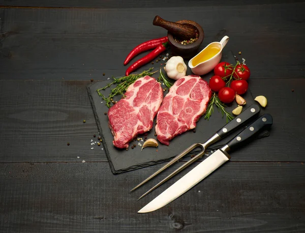 Carne fresca cruda o filetes de cerdo en tabla de servir de corte de piedra — Foto de Stock