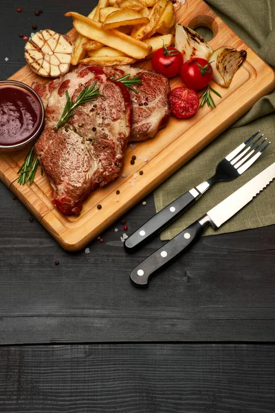 Жареная говядина стейки, картофель и соус на деревянной доске — стоковое фото
