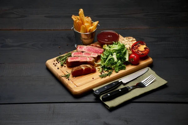 Gegrilde biefstuk, aardappel en saus op houten snijplank — Stockfoto