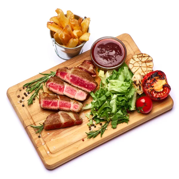 Grilled sliced roated beef steaks, potato and sauce on wooden cutting board — Stock Photo, Image