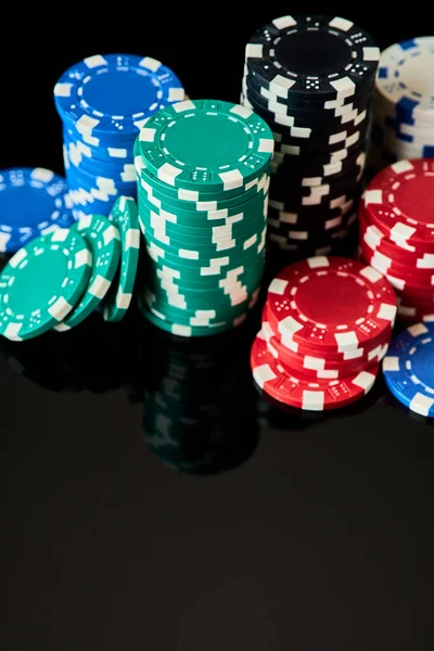 Stack of Casino gambling chips isolated on black reflective background — Stock Photo, Image