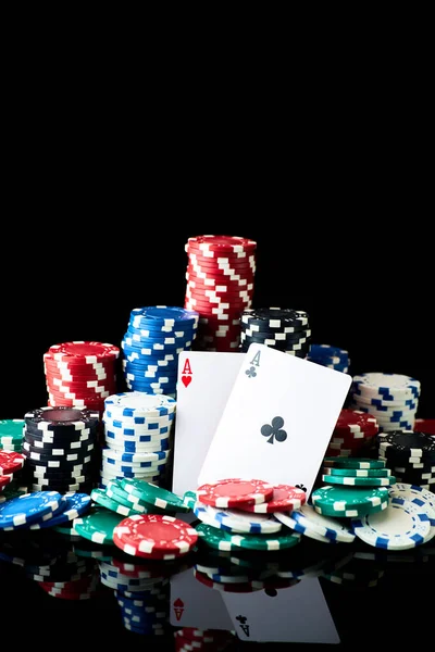 Stack of Casino gambling chips and cards isolated on black reflective background — Stock Photo, Image