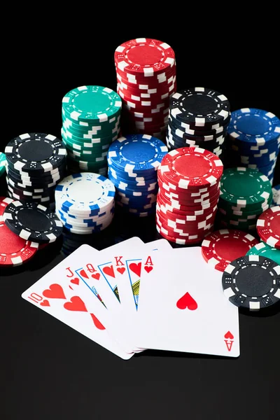 Stack of Casino gambling chips and cards isolated on black reflective background — Stock Photo, Image