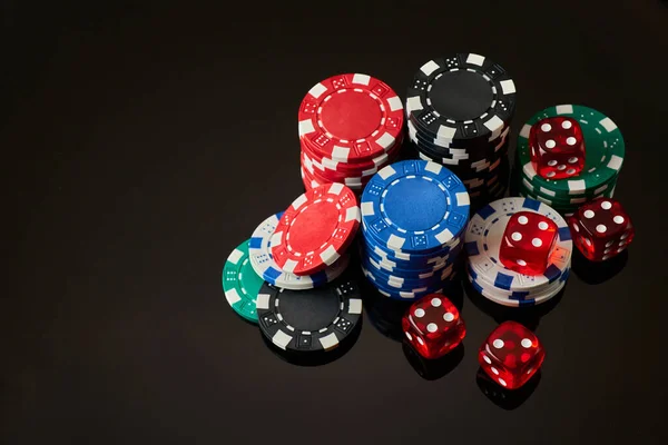 Casino chips and dices on dark reflective background with copy space — Stock Photo, Image