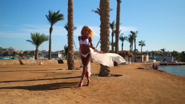 Giovane donna di moda che indossa pareo a piedi sulla spiaggia — Video Stock