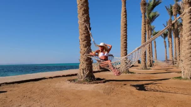 Концепція подорожей та відпусток - жінка відпочиває на гамаку на пляжі — стокове відео