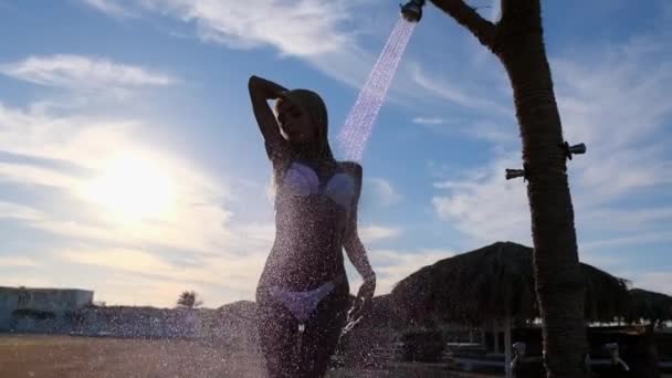 Divat modell visel bikini vesz egy pihentető zuhany trópusi strandon — Stock videók