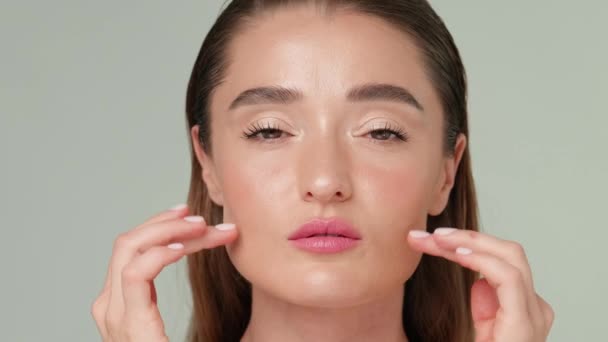 Gyönyörű fiatal nő tiszta friss bőr áll a fény szürke háttér — Stock videók