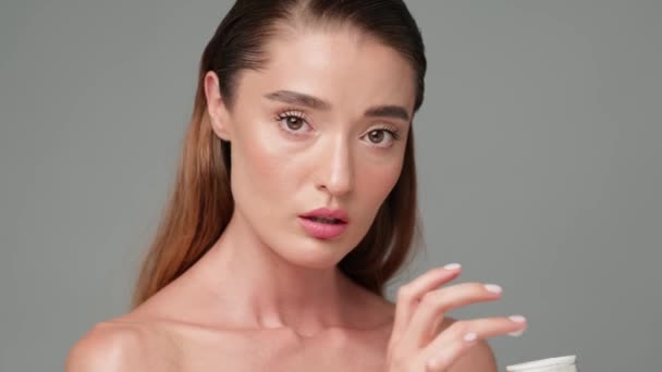 Vacker ung kvinna med ren fräsch hud står över ljusgrå bakgrund — Stockvideo