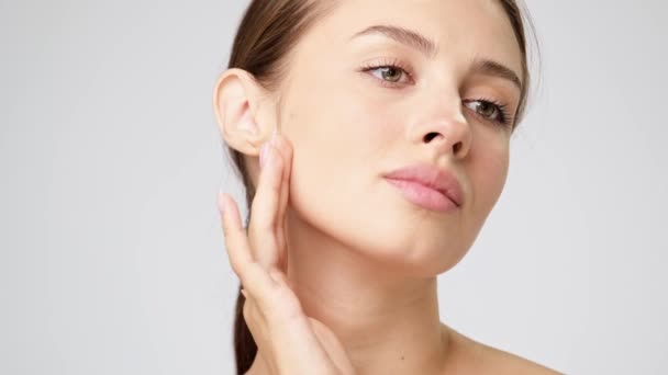 Beautiful Young Woman with Clean Fresh Skin standing over light grey background — Stock Video