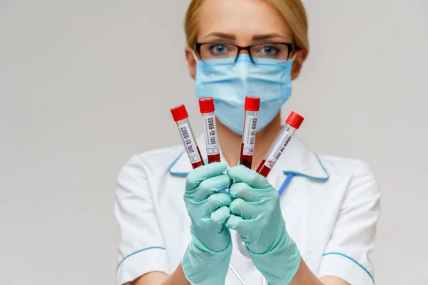 Läkare sjuksköterska kvinna bär skyddsmask och handskar - hålla virus blodprov röret — Stockfoto