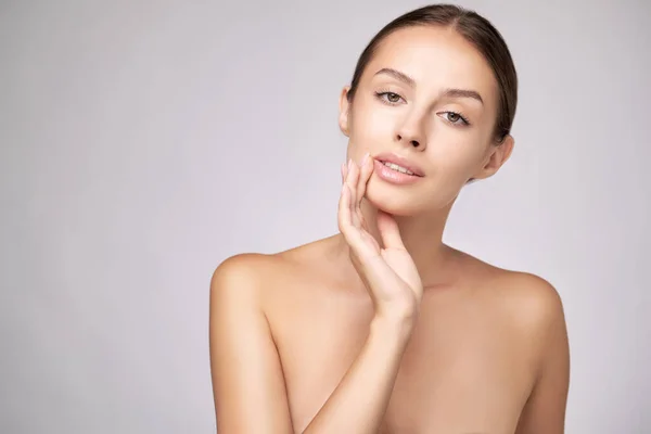 Mooie jonge vrouw met schone frisse huid staande over lichtgrijze achtergrond — Stockfoto