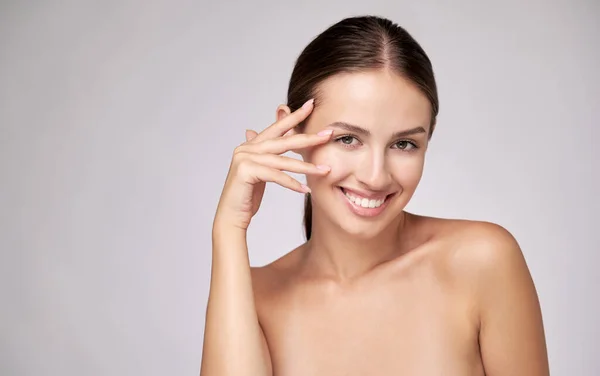 Mooie jonge vrouw met schone frisse huid staande over lichtgrijze achtergrond — Stockfoto