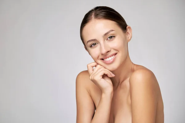 Mooie jonge vrouw met schone frisse huid staande over lichtgrijze achtergrond — Stockfoto