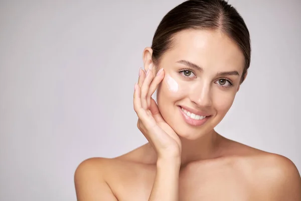 Mooie jonge vrouw met schone frisse huid staande over lichtgrijze achtergrond — Stockfoto