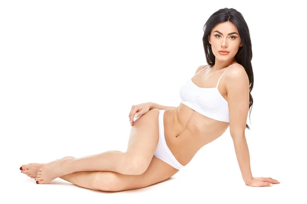 Fitness junge Frau mit einem schönen Körper sitzt auf weißem Hintergrund — Stockfoto