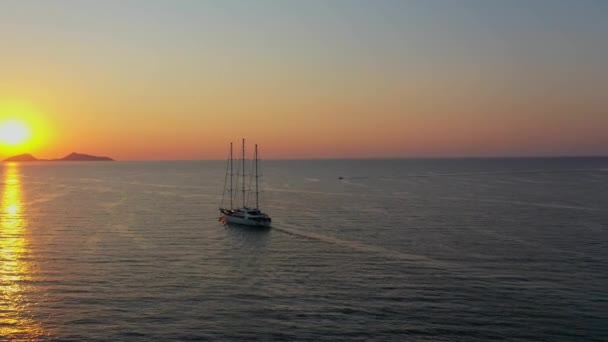 クルーズ船の空中ドローンビデオは、オレンジの夕日を背景に帆 — ストック動画