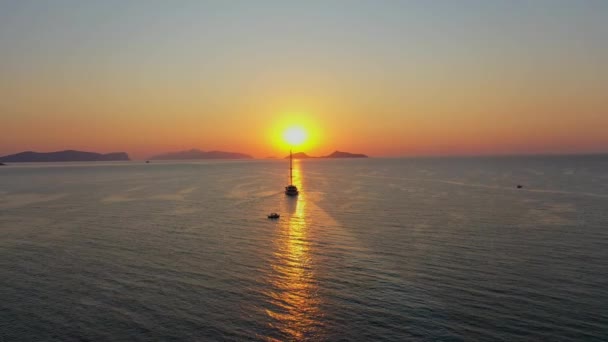 クルーズ船の空中ドローンビデオは、オレンジの夕日を背景に帆 — ストック動画