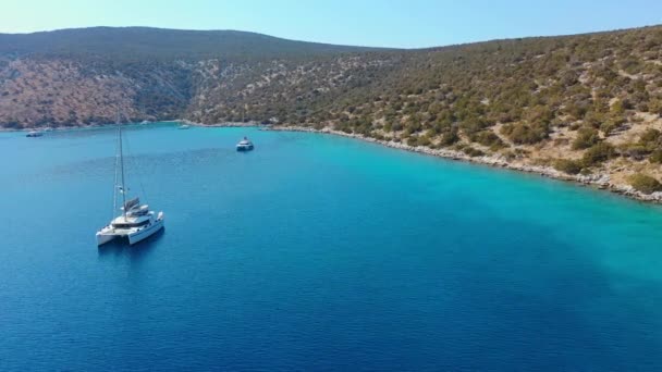 Katamarán a plachty Jachty zakotvené v zátoce na hluboké modré mořské vodě při východu slunce — Stock video