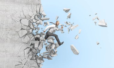 Gülümseyen işadamı beton bir duvardan atlar ve geçer. Güç ve kararlılık kavramı..