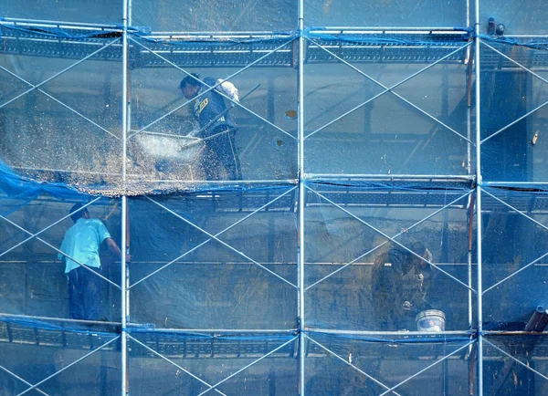 Trabajadores de la construcción en lo alto de andamios — Foto de Stock