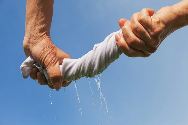 Mani spremere tessuto bagnato contro il cielo blu . — Foto Stock