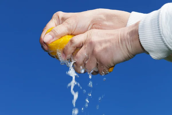 Hands squeeze wet fabric against blue sky. — Stock Photo, Image