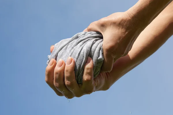 Mani spremere tessuto bagnato contro il cielo blu . — Foto Stock