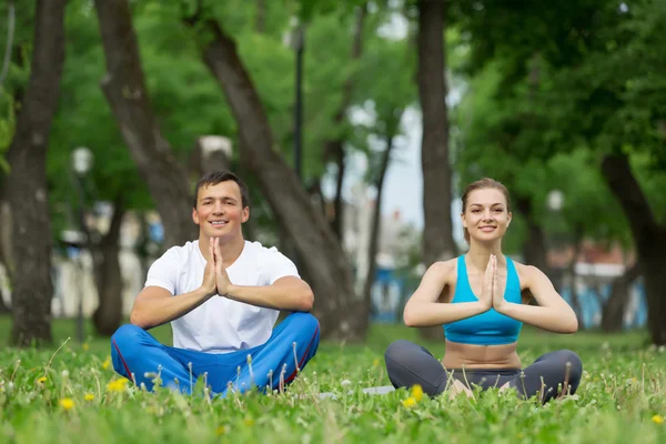 Young couple meditating on green grass — Stock Photo, Image