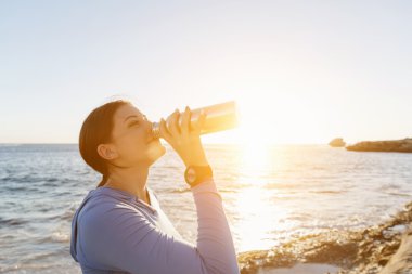 Kumsalda su içen kadın