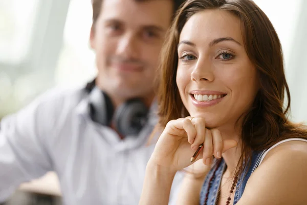 Joven bonita mujer sonriendo con el hombre en el fondo —  Fotos de Stock