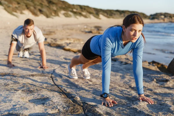 Giovane coppia facendo push up sulla spiaggia dell'oceano — Foto Stock