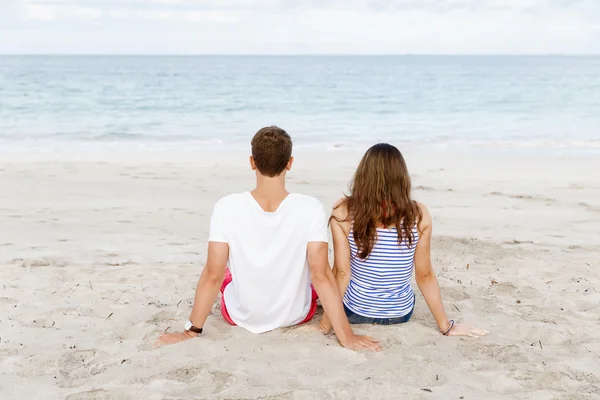 Romantiska unga paret sitter på stranden — Stockfoto