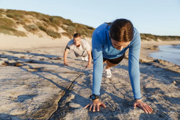 Mladý pár dělá push up na ocean beach — Stock fotografie
