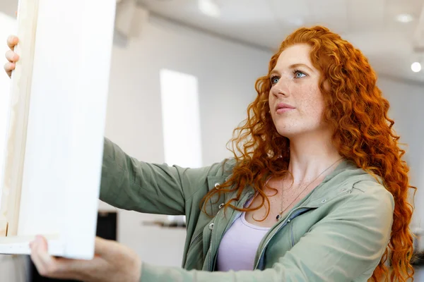 Jonge Kaukasische vrouw permanent in kunst galerij voor schilderijen — Stockfoto