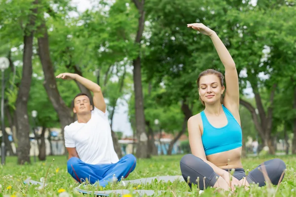 Jovem casal meditando na grama verde — Fotografia de Stock