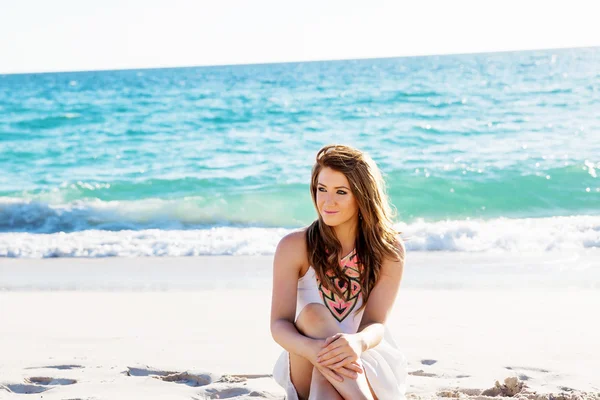 Jonge vrouw zittend op het strand — Stockfoto