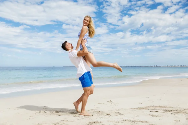 Casal feliz pulando em férias na praia — Fotografia de Stock