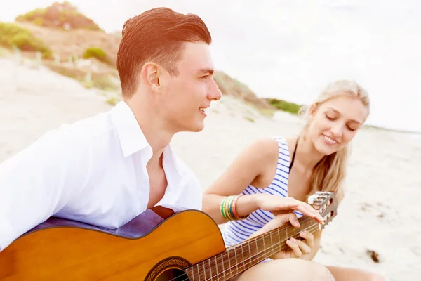 Jong koppel gitaarspelen op strand in liefde Rechtenvrije Stockfoto's
