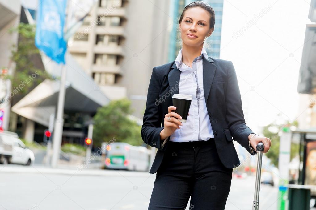 Business woman pulling suitcase walking in city