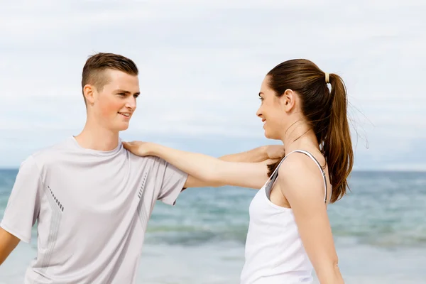 Corredores. Pareja joven haciendo ejercicio y esteretizando en la playa —  Fotos de Stock