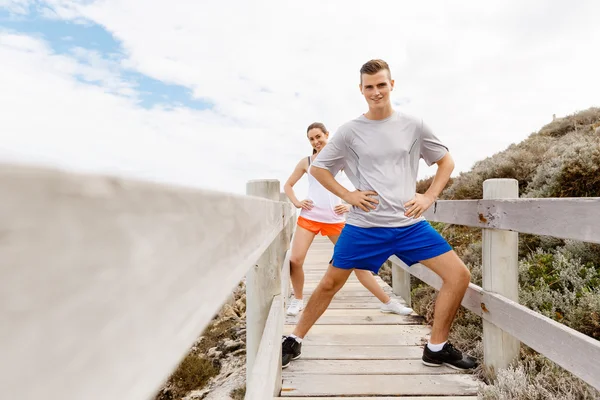 Läufer. junges Paar beim Turnen und Stertching am Strand — Stockfoto