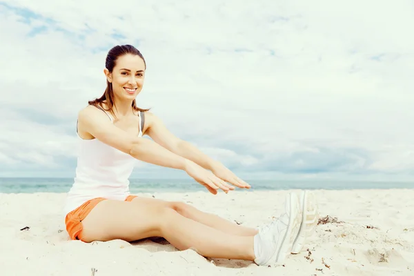 Junge Frau trainiert draußen am Strand — Stockfoto
