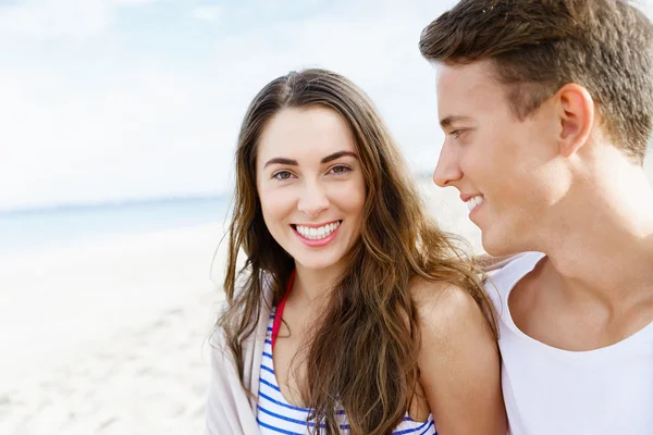 Romántica pareja joven sentada en la playa — Foto de Stock