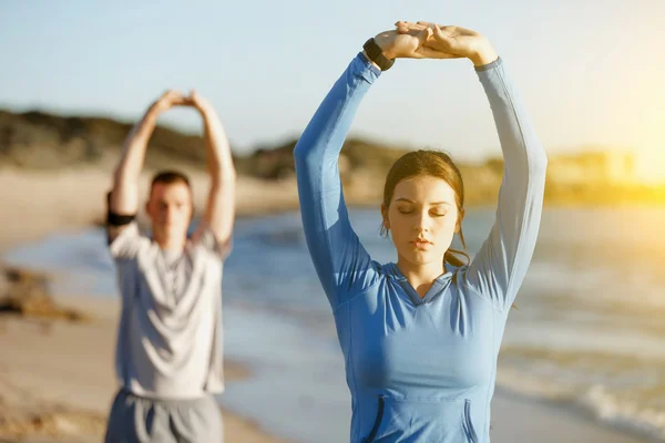 Jeune couple sur la plage d'entraînement ensemble — Photo