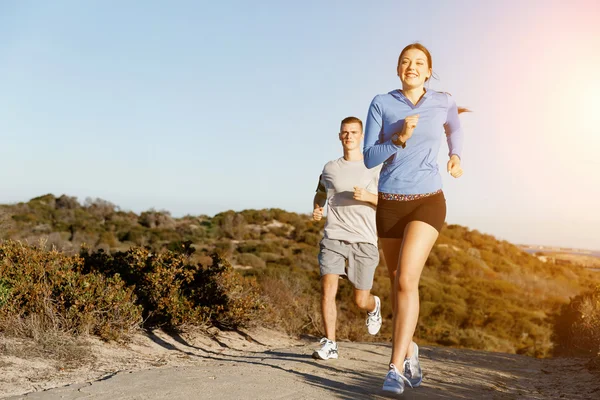Corredor deportivo trotando en la playa haciendo ejercicio con su pareja — Foto de Stock