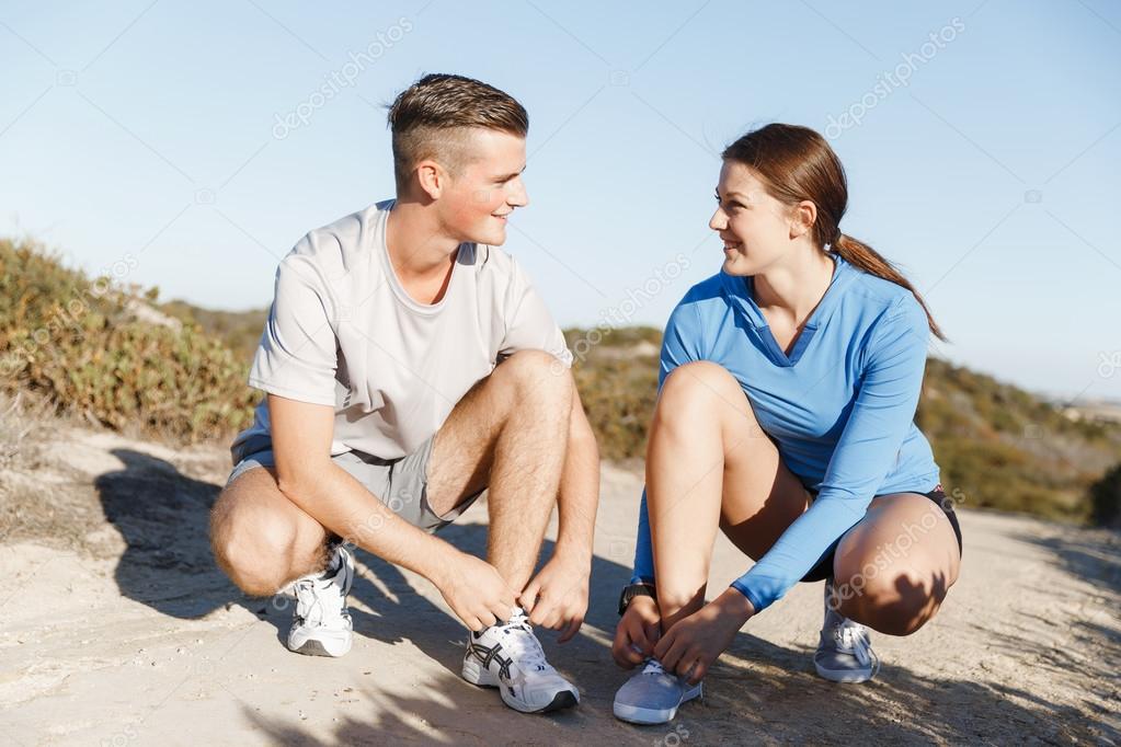 Couple of runners lace their shoes and prepare to jogging