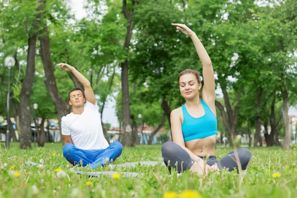 Jeune couple méditant sur l'herbe verte — Photo