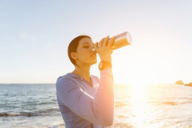 Kumsalda su içen kadın