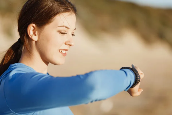 Mujer corredora con monitor de frecuencia cardíaca corriendo en la playa —  Fotos de Stock